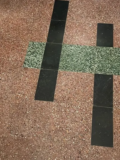 Testing new tile samples against the original terrazzo flooring, a part of our process to ensure new interventions are sympathetic to the original design.