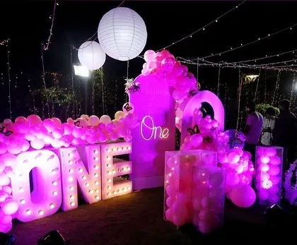 The pink-themed first birthday party at night, with all the lights and balloons creating a magical glow.