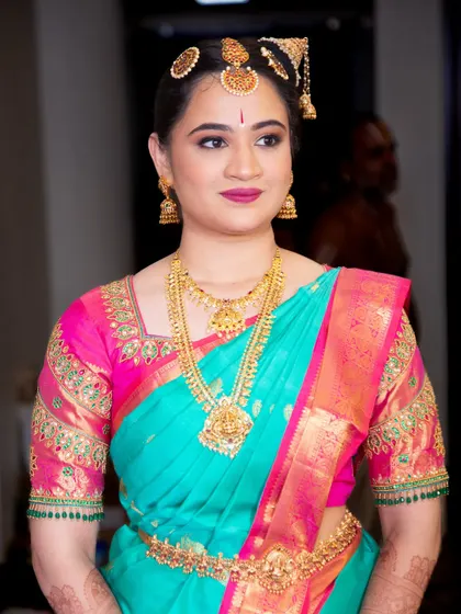 A classic portrait of Vibha on her Muhurtham day. The makeup features a flawless base that enhances her skin tone, paired with a beautiful turquoise and pink saree.