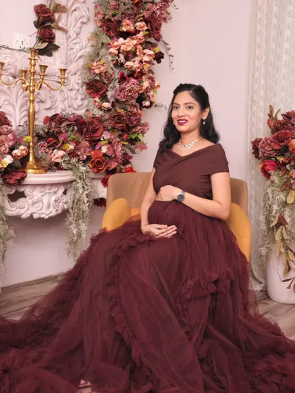 A seated portrait that showcases the magnificent trail of the gown. This pose exudes royalty and grace, perfect for a maternity photoshoot.