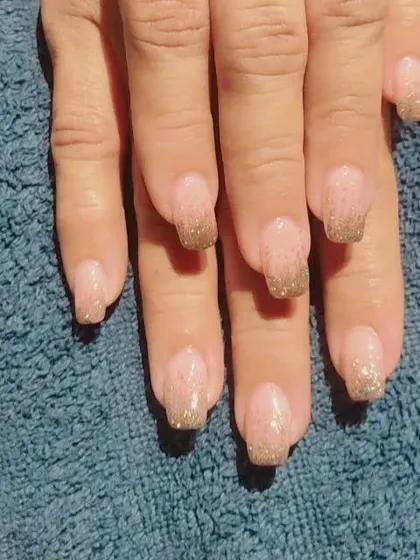 Another example of the gold glitter fade French manicure, showing how it looks on a different hand against a neutral background.