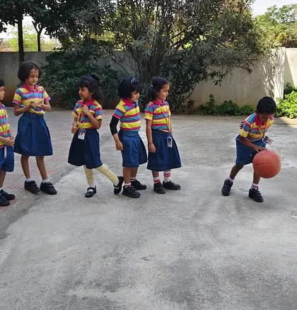 A group of preschoolers lines up for their turn to practice dribbling, learning teamwork and coordination through basketball.