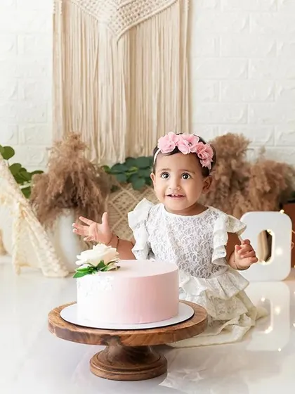 A pre-cake smash portrait in a boho setup, with the birthday girl ready and waiting for her cake.