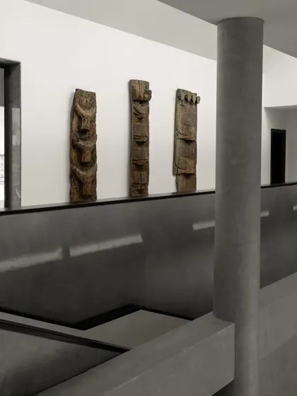 A view from the upper level of the House Around the Oblique Column, showcasing the interplay of concrete planes and voids. The space doubles as a gallery for tribal art, its minimalist aesthetic providing a stark, powerful backdrop.