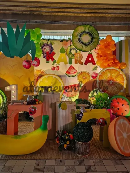 This wide shot of the main decor area shows how I combine large 3D fruit props, a light-up number "1", and a custom name banner to create a stunning focal point for a first birthday.
