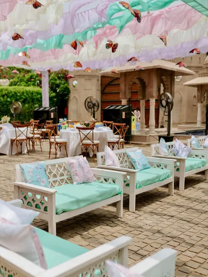 Comfortable and chic divan seating for guests, with pastel cushions that match the ruffled ceiling drapes and butterfly theme.