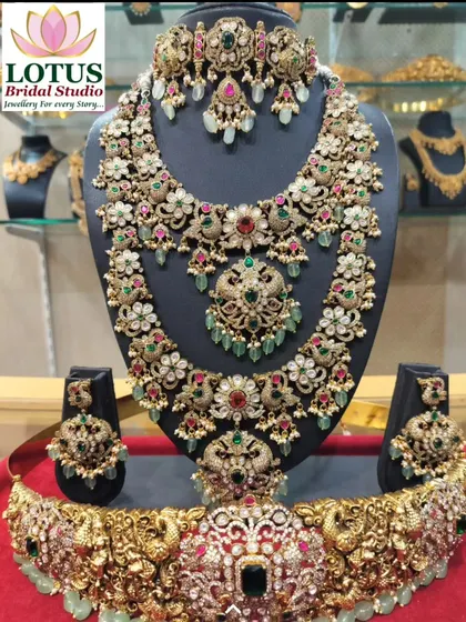 A grand Victorian-style bridal set with a mix of red, green, and white stones, complete with a matching vaddanam.
