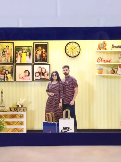 A blue velvet miniature box showing a couple in matching outfits. The room is decorated with an Eiffel tower, a 'love' sign, and a wall of family photos.