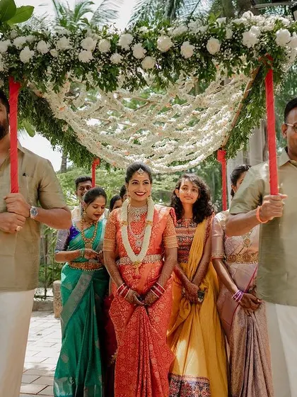 The bride's grand entrance under a beautiful floral canopy. This shot captures the tradition and elegance of a Telugu wedding ceremony.