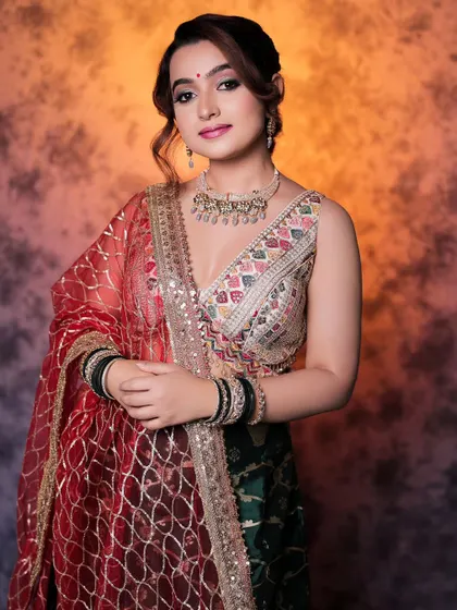 A beautiful studio portrait of a model in a multi-colored lehenga. The warm, textured background complements the outfit and creates a rich, festive feel.