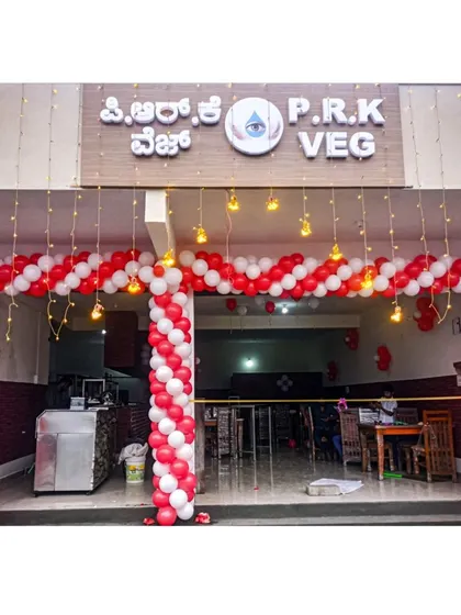 A grand entrance for a hotel's opening ceremony. This large red and white spiral balloon arch, accented with hanging incandescent bulbs, creates a celebratory and professional welcome for guests and patrons.