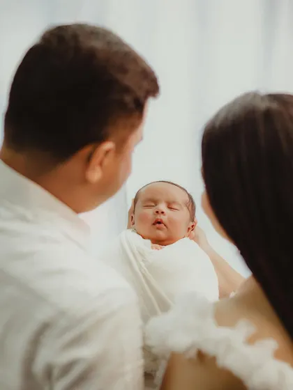 An over-the-shoulder shot of parents adoring their newborn baby. This perspective creates a sense of intimacy and love.