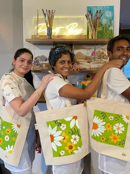 Three proud artists showing off their floral-themed tote bags. Our tote bag workshops are a great way to express your personal style.