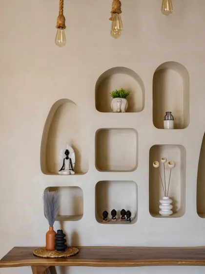 In the living area, we carved organic niches into the wall to create a unique display for art and accessories. This detail adds a soft, sculptural quality to the space, complementing the villa's natural aesthetic.