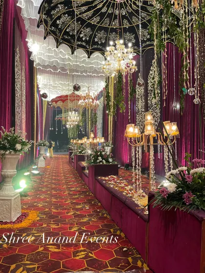 An opulent walkway featuring plush velvet seating, ornate candelabras, and intricately designed umbrellas hanging from the ceiling.
