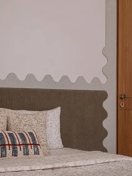 A detail of the daughter's bedroom, showing the wavy, textured headboard and custom-printed pillows.