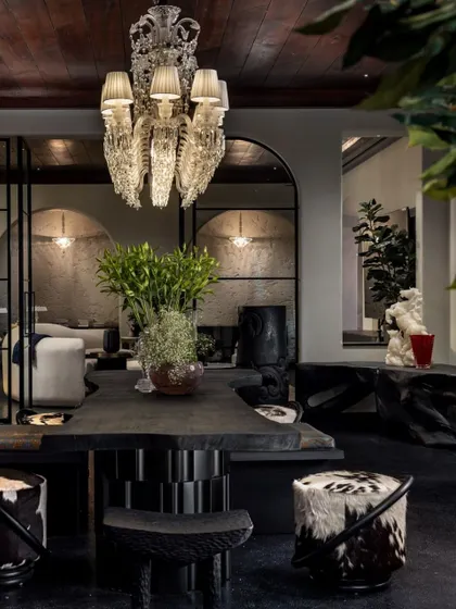 The entertainment lounge in the House of Two Worlds is designed for adaptability and scale. A dramatic chandelier hangs over a live-edge table, surrounded by an eclectic mix of seating that can be configured for intimate gatherings or large parties.
