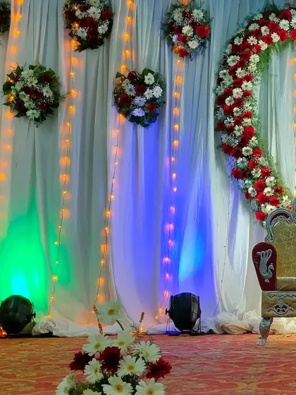 This stage features a large heart-shaped floral arch made of red and white flowers. Paired with hanging floral bouquets and string lights, it creates a beautiful and romantic focal point for an engagement or reception.