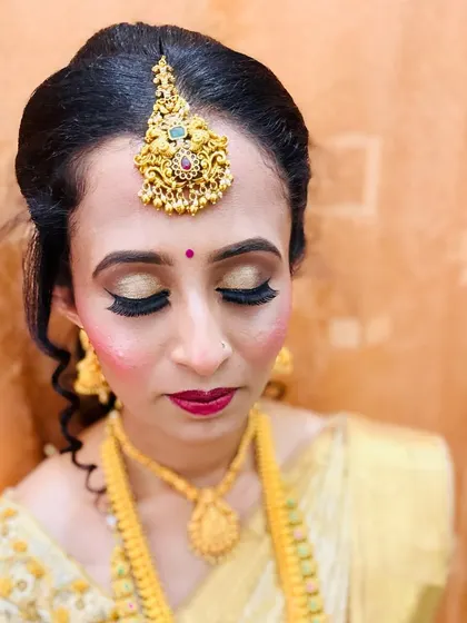 A close-up of Chitra's reception eye makeup. The golden eyeshadow and dramatic lashes make her eyes the center of attention.