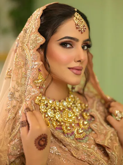 A soft and dreamy bridal look in a peach lehenga. The makeup is kept subtle with a focus on glowing skin, soft brown smokey eyes, and a natural lip colour.