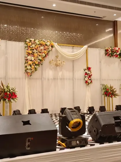 For indoor receptions, I create elegant and modern stages. This setup features a clean white fabric backdrop, delicate pastel floral arrangements, and a small chandelier, perfect for a sophisticated banquet hall wedding.