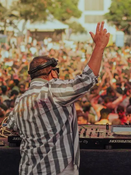 A view from behind the decks at a Holi festival. A sea of colorful, happy people dancing.