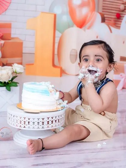 A wide shot of the cake smash setup, showing the birthday boy enjoying his cake with a festive backdrop of gifts and a rocking horse.