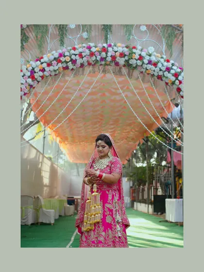 The bride standing under a beautifully decorated floral archway. This shot captures her in a moment of solitude before her grand entrance.
