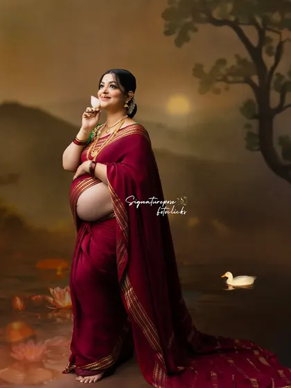 A dreamy, artistic portrait with a painted lake backdrop, where the mother holds a lotus flower.