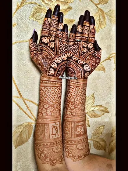 A gorgeous engagement mehendi with personalized initials. The design includes beautiful elephant motifs and intricate jaali patterns, covering the arms from elbow to fingertips.