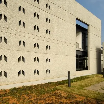 The patterned facade of the main building block. The rhythmic placement of angular window openings creates a distinctive architectural feature while controlling the amount of direct sunlight entering the interior spaces.