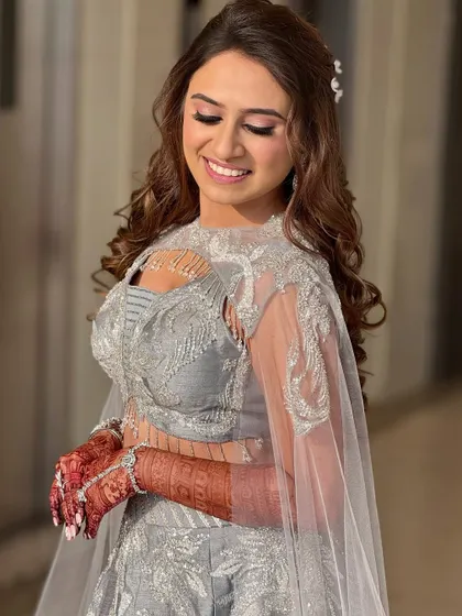 A vision in silver for her sangeet night. This look features highly defined, glittery eyes and a soft lip, letting the eyes do all the talking. The sleek hair completes this modern and chic look.