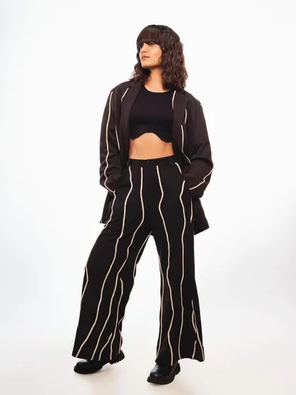 A full-length shot for Schwarzkopf's "Beatniks" trend. The makeup is minimal and modern, with a focus on clean skin, which supports the edgy, textured hairstyle and monochrome outfit.