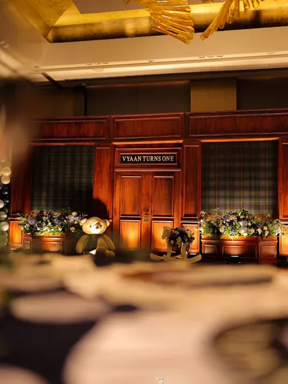 An artistic shot looking across a detailed tablescape towards the main stage. This perspective highlights the layers of our design, from the foreground details to the grand backdrop of this special first birthday.