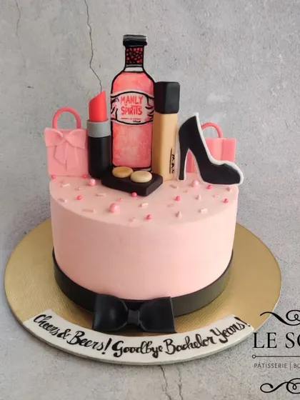 Perfect for a bride-to-be's celebration, this cake combines all her favorite things. This 1 kg lamington-inspired cake features fondant makeup, shopping bags, and a bottle of "Manly Spirits" for a fun touch.