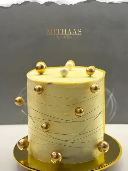 What does the world's dreamiest cake look like? For me, it's this tall, elegant creation with a pale yellow frosting, fine chocolate string work, and floating golden spheres.