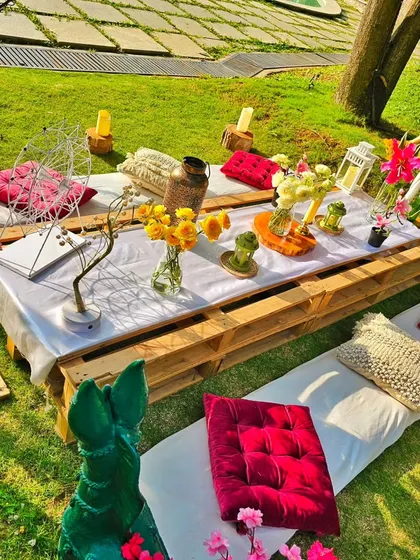 A closer look at the rustic-chic picnic table, showing the mix of fresh flowers, cushions, and decorative items that create a relaxed and beautiful atmosphere.
