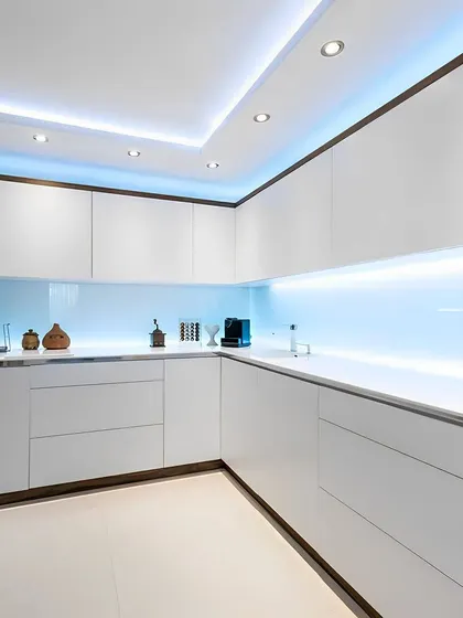 A futuristic all-white kitchen with cool blue LED backlighting. The high-gloss, handleless cabinets create a seamless and ultra-modern look.