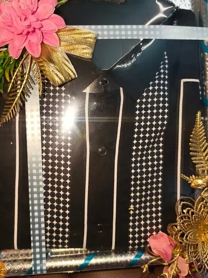 A close-up of a packed formal shirt for the groom. The silver box and floral decorations make it look very special.