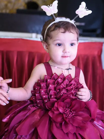 A close-up portrait of the adorable first birthday girl in her beautiful magenta dress and butterfly headband.