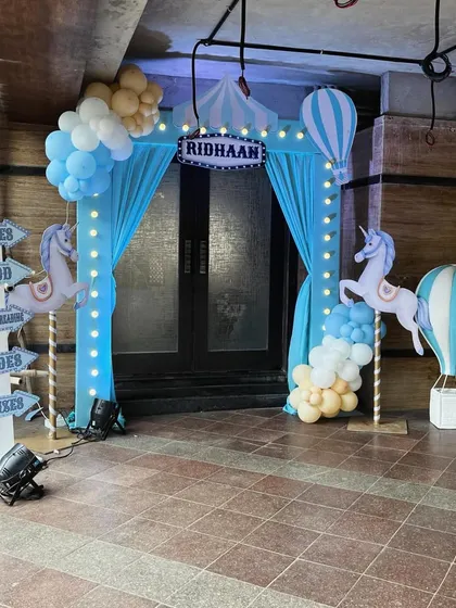 The entrance to Ridhaan's carnival, with glowing lights, carousel unicorns, and hot air balloon props.