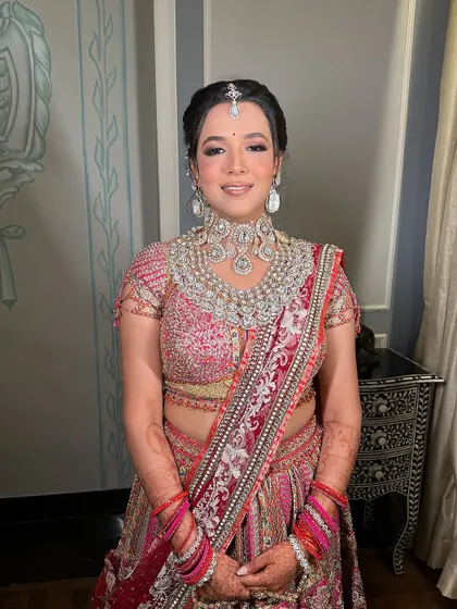 The bride is all smiles, her floral bun hairstyle perfectly complementing her stunning Tarun Tahiliani bridal lehenga.