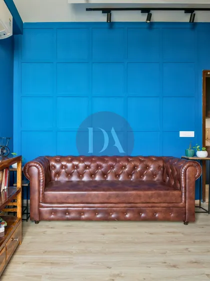 We love to play with color to reflect your personality. This bold blue accent wall, featuring classic paneling, creates a dramatic yet sophisticated backdrop for a timeless leather Chesterfield sofa, showcasing how color can define a room's character.