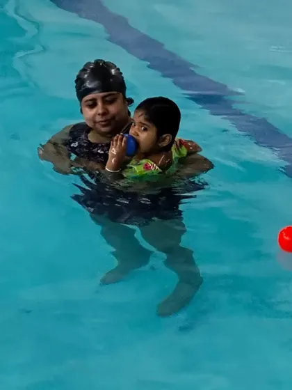 A parent holds their child in the water during a lesson, demonstrating the parent-assisted approach of our toddler program.