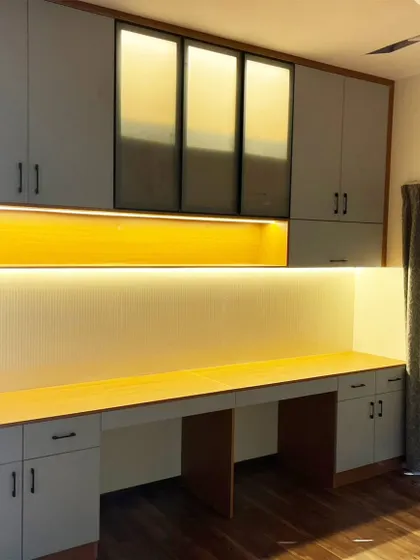 This custom unit combines a long study desk for two with ample overhead storage. The matte laminate finish, aluminum-framed glass doors, and integrated backlighting create a workspace that is both functional and stylish.