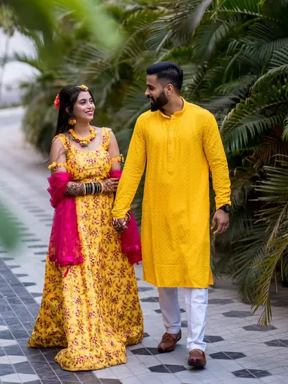 A happy, walking shot of the couple holding hands during their Haldi celebration, capturing their movement and joy.