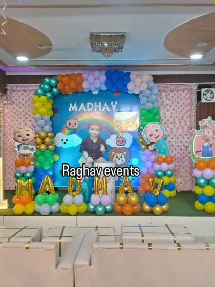 A complete Cocomelon themed stage decoration for Madhav's first birthday. This setup includes a custom backdrop, character cutouts, balloon letters spelling the name, and a light-up number '1'.