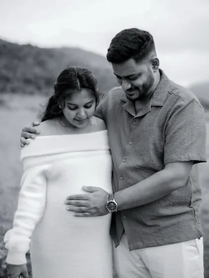A black and white photo of the couple sharing a quiet moment. They both look down at the baby bump, a shared moment of wonder and love for their unborn child.