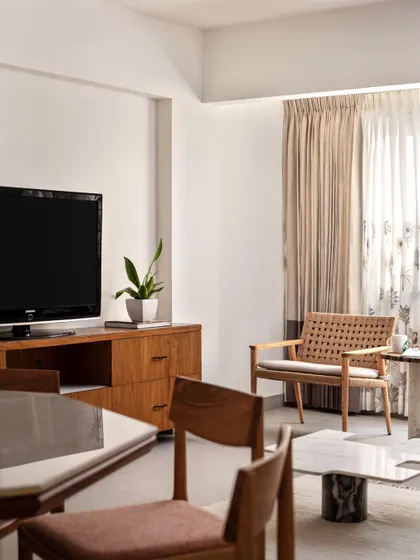 The family lounge's television wall with a floating console. The space is designed to be cozy and clutter-free, with simple seating and chic marble tables.