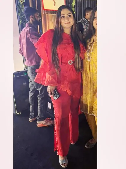 A bold and stylish statement. This client is wearing a custom red set featuring an organza frill top with a belt and paired with elegant pearl-cut pants.